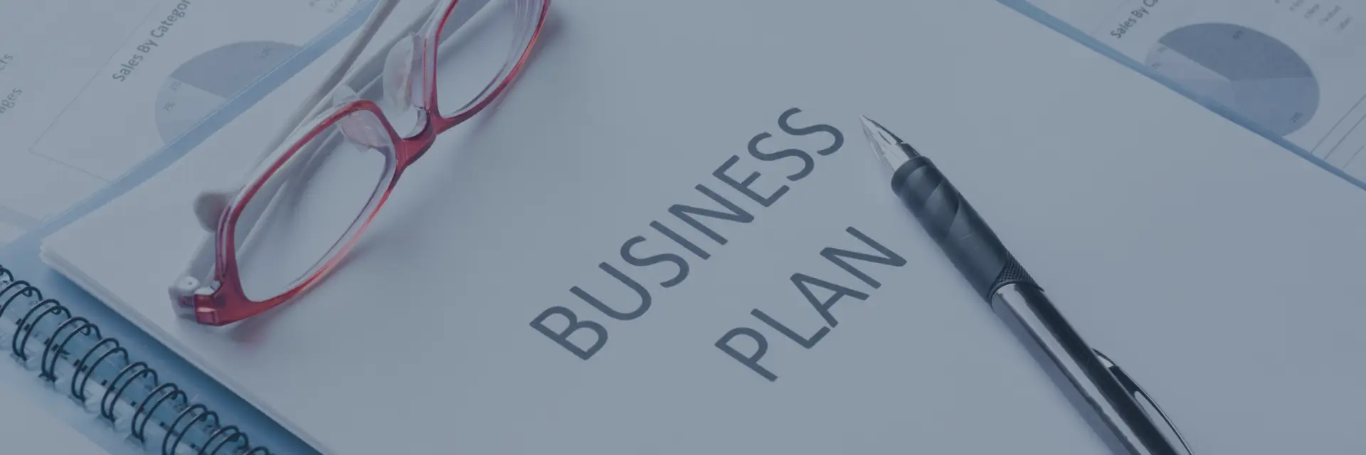 Aufgeschlagener Businessplan auf dem Schreibtisch eines Gründers